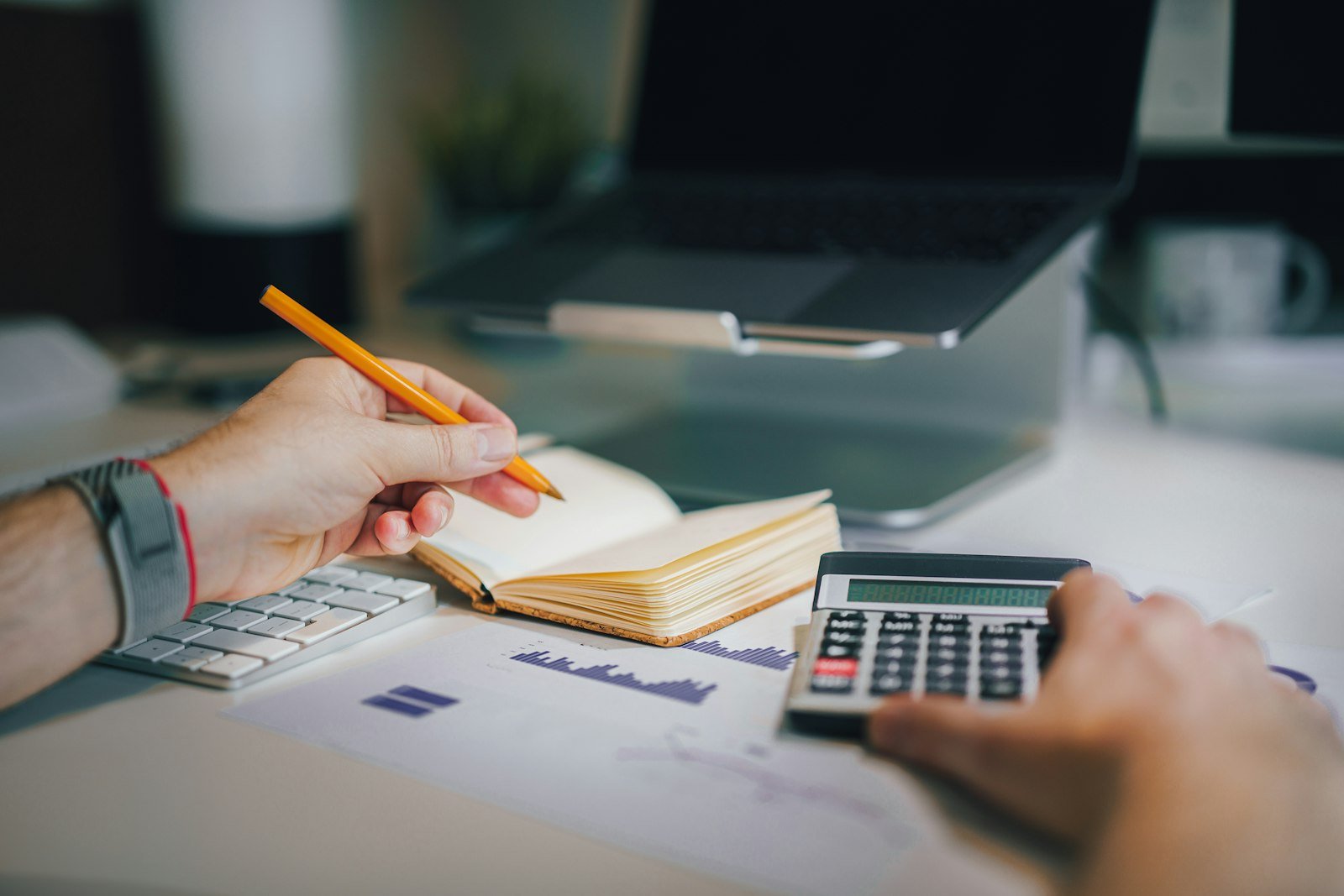 Business owner sitting at a desk with a calculator and notebook, weighing a financial decision